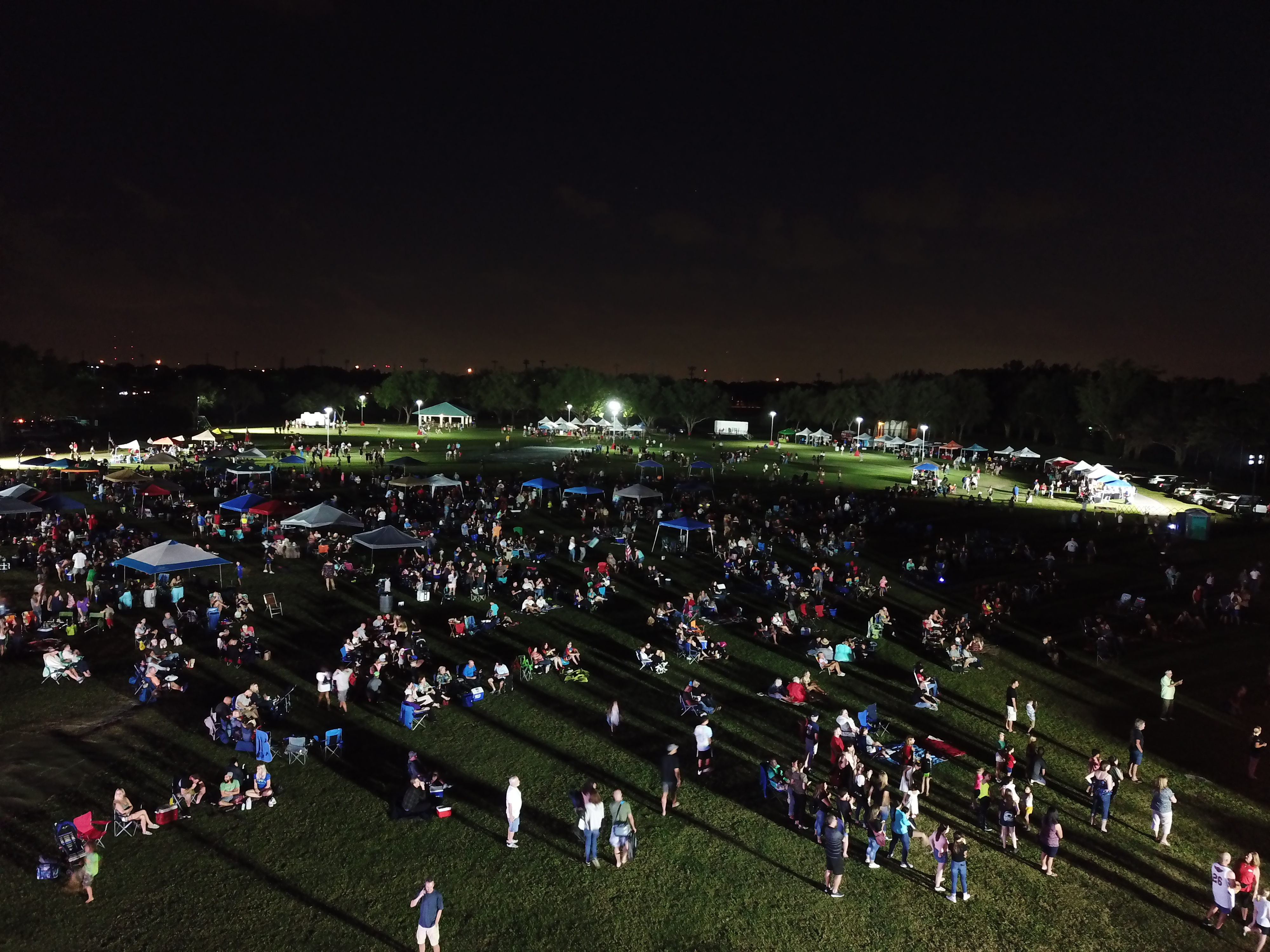 Crowd camped out at night to listen to music on grass field